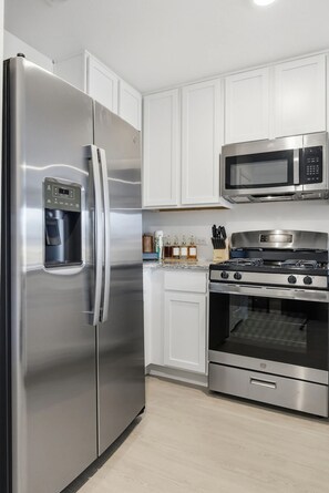 A modern kitchen with stainless steel appliances, including a refrigerator, microwave, and oven. - Brand New 3BR House - Game Day Ready - 2.4 Miles to OU - With Garage - Sleeps 7 (Norman)