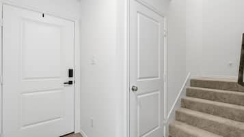 A hallway with two white doors, a carpeted staircase, and a light switch on the wall.