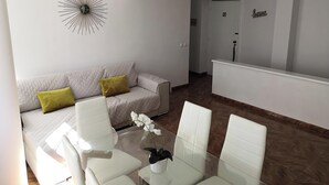A modern living room with a sofa, chairs, a glass coffee table, and a decorative wall piece.