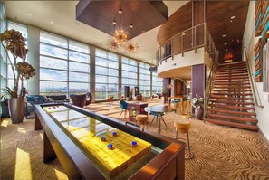 A spacious lobby with a pool table, comfortable seating, large windows, and a staircase. - Landing | Modern 1BD, Yoga Studio, Gym (Houston)