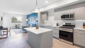Een moderne keuken met een centraal eiland, roestvrijstalen apparatuur en een blauwe accentmuur.