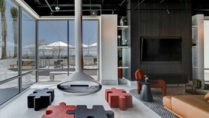 Een moderne lounge met een grote televisie, zitplaatsen en uitzicht op de omgeving.