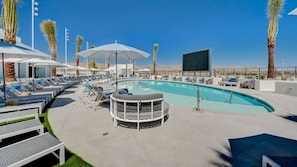 Ein Poolbereich mit Liegestühlen, Sonnenschirmen und einer Bar.