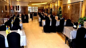 A banquet hall with rows of tables set for dining, a marble wall, and a ceiling with recessed lighting. - Mira Al Rawda Hotel Makkah (Makkah)