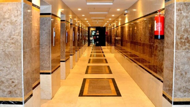 A corridor with marble walls and a tiled floor, leading to a door at the end. - Mira Al Rawda Hotel Makkah (Makkah)