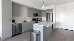 A modern kitchen with grey cabinets, stainless steel appliances, and a central island. - Landing | Amazing 2BD, Pool, Rooftop Lounge (Spring Valley)