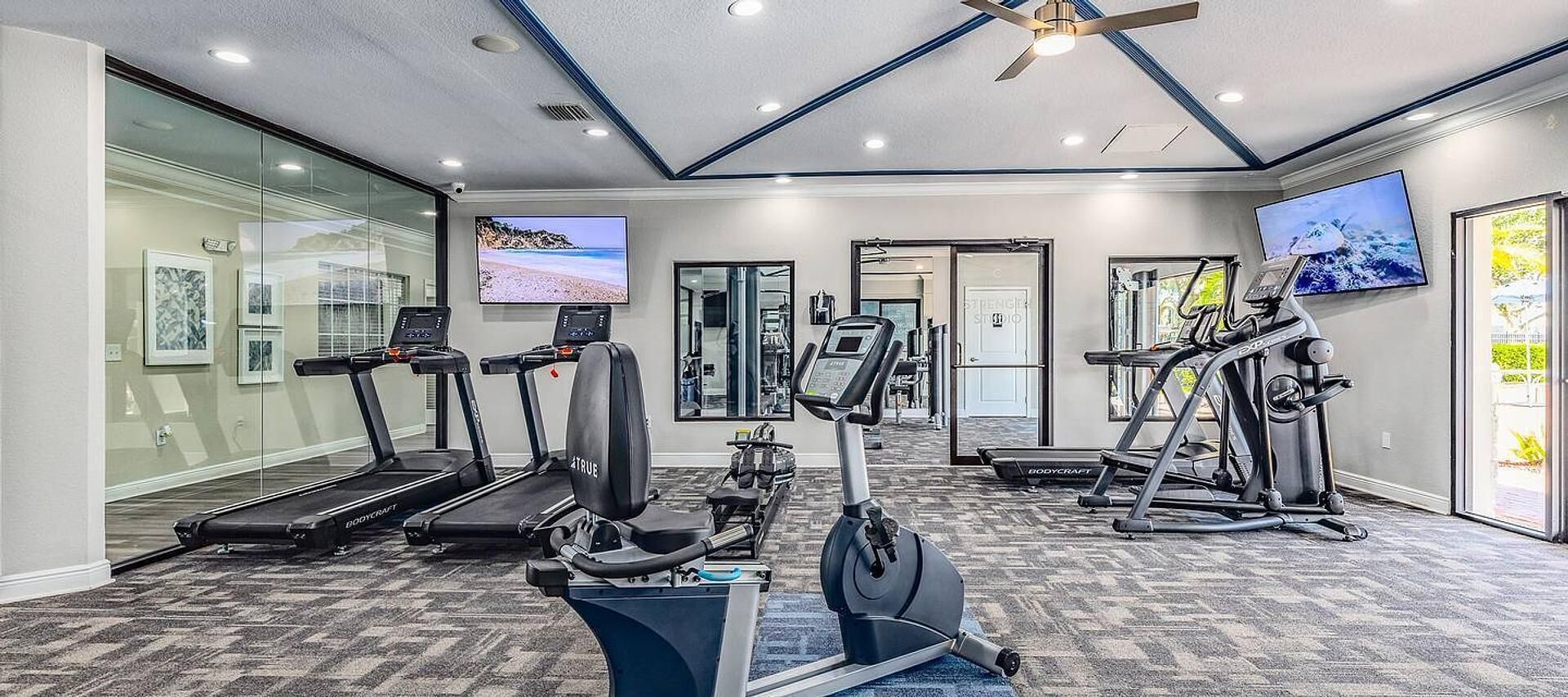 A gym with treadmills, an elliptical, and weight machines.