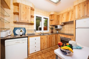 Une cuisine avec des meubles de rangement en bois, une fenêtre, un four à micro-ondes et un lave-vaisselle.