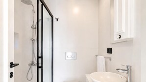 Un bagno moderno con cabina doccia in vetro, un water bianco e un lavabo grande con bacino a incasso.