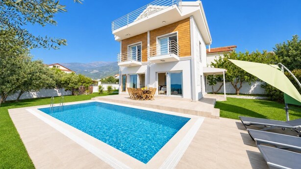 Una casa a due piani con piscina, mobili da esterno e vista sulle montagne.