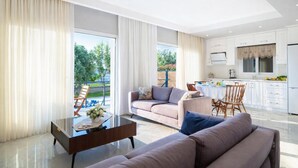 A modern living room with a sofa, coffee table, and dining area with chairs. - Villa Riva - Three Bedroom Villa, Sleeps 6 (Oludeniz)