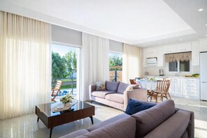 Un salon moderne comprenant un canapé, une table basse et un coin repas avec des chaises.
