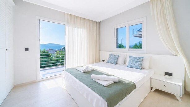 A bedroom with a bed, a nightstand, a window with a view, and a sliding door to a balcony. - Villa Riva - Three Bedroom Villa, Sleeps 6 (Oludeniz)