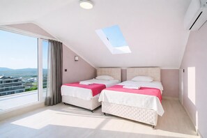 Une chambre avec deux lits, une lucarne, une grande fenêtre et une vue sur les immeubles.