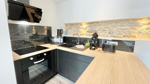 A modern kitchen with a black stove, a sink, and a stone backsplash. - 4★ Renovated Studio with Wifi, 5 min Walk to Quimper Station (Quimper)