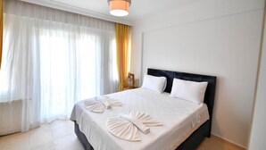 Ein Hotelzimmer mit einem großen Bett, weißen Leinentüchern, einem schwarzen Kopfteil und einer modernen Pendelleuchte.