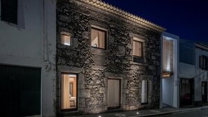 A stone building with three windows, each with a curtain. - North Shore Hostel (Ribeira Grande)