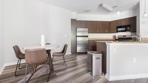 Una cocina moderna con una isla central, electrodomésticos de acero inoxidable y una zona de comedor con dos sillas.
