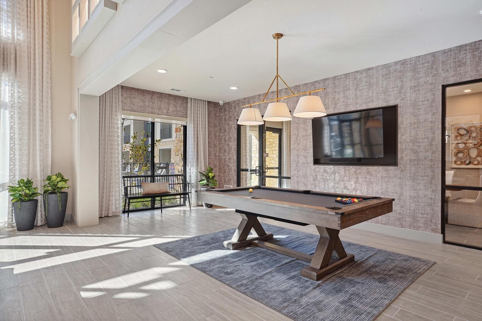 Une pièce spacieuse équipée d’une table de billard, d’un coin salon confortable et d’un grand téléviseur fixé au mur.