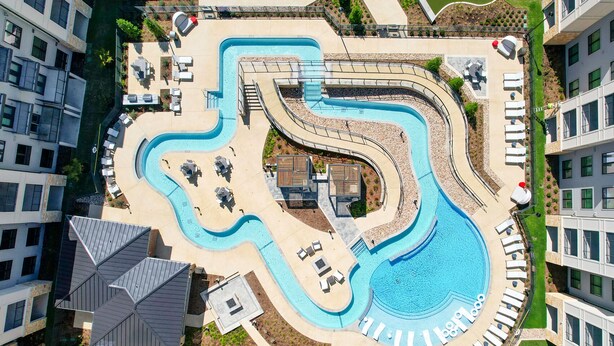 A large, winding swimming pool surrounded by lounge areas and outdoor seating. - Landing | Spectacular 1BD, Yoga Studio, Pool (Anna)