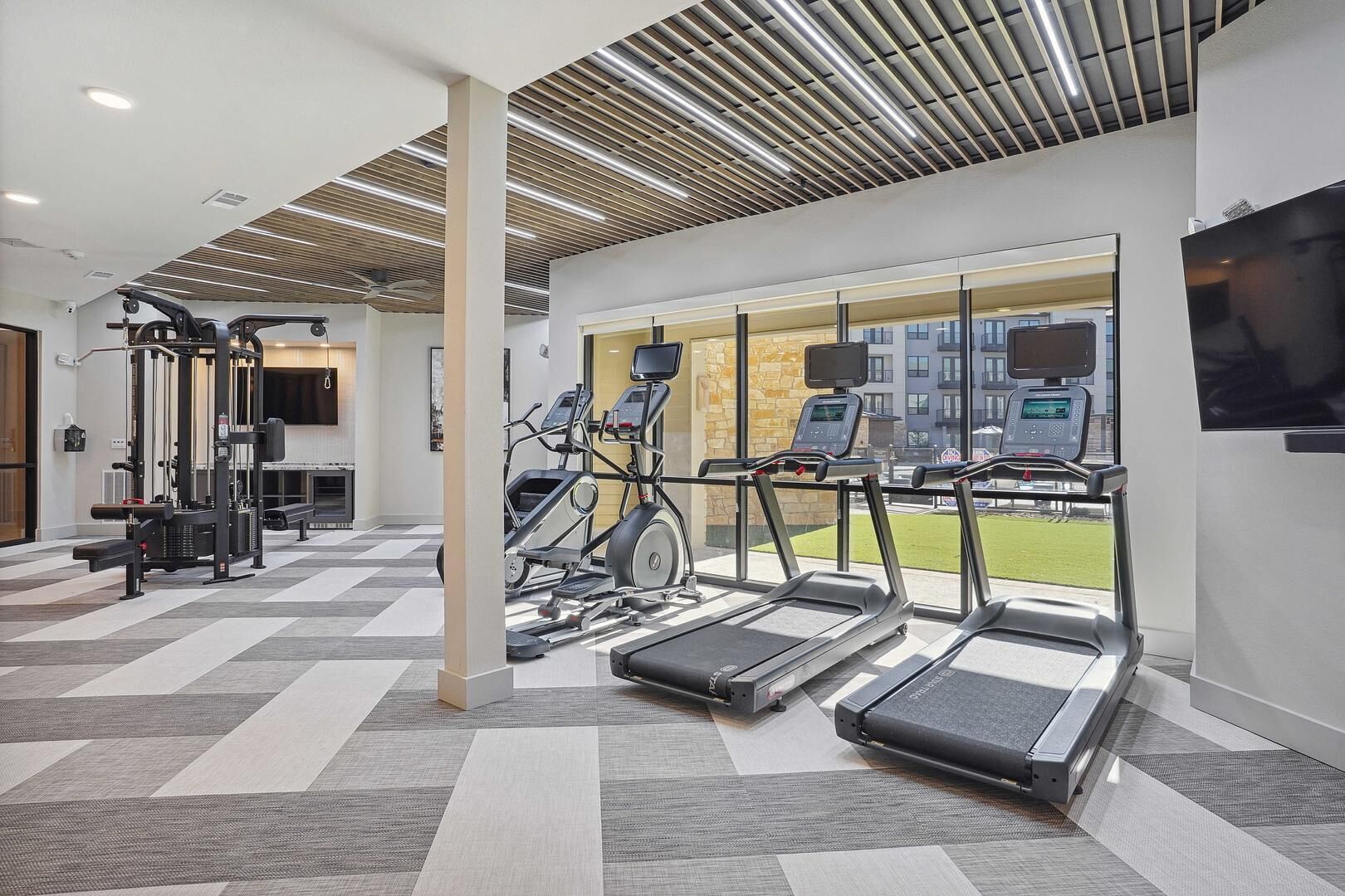 Une salle de sport moderne équipée de tapis de course, de vélos elliptiques et de matériel de musculation.