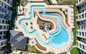 Ein großer, geschwungener Pool, umgeben von Liegebereichen und Gartenmöbeln.