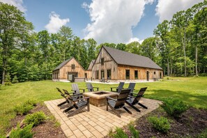 A rustic wooden cabin with a large deck and outdoor seating area. - New! Modern Lake Area Home w/ Hot Tub! (Oakland)