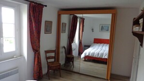 Een slaapkamer met een bed, een stoel, een spiegel en een raam.