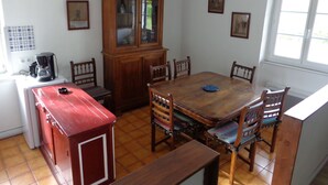 Een eethoek met een houten tafel, stoelen, een kast en een koffiezetapparaat.