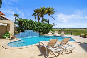 A swimming pool with lounge chairs, a tiled wall, and palm trees in the background. - 3BR Pool Villa w/ Golf Views, Tierra del Sol (Noord)
