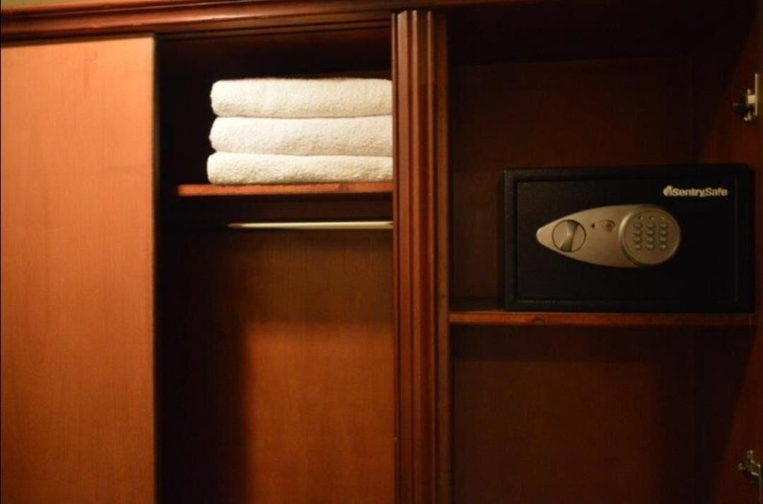 Un meuble en bois muni d’un porte-serviettes où sont rangés des serviettes pliées et d’un coffre-fort à clavier.