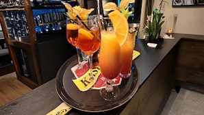 En bardisk med ett bricka fullt med drinkar, en tv-skärm och en växt på disken.