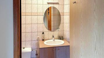 Ein Badezimmer mit rundem Spiegel, Waschbecken und Toilette.