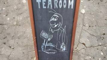 A chalkboard sign with the word "TEAROOM" and a drawing of a person with a telescope and a plant.