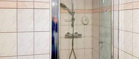 A shower with a handheld showerhead and a wall-mounted control panel.