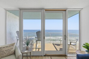 Une chambre dotée d’une porte-fenêtre coulissante donnant sur un balcon avec vue sur la plage.