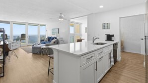 Una cocina moderna con una isla grande, un comedor con vistas y una sala de estar con sofá y mesa de centro.