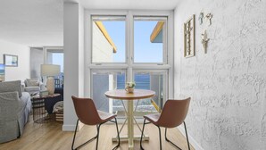 Una habitación con una mesa redonda, dos sillas, un sofá y vistas amplias a través de ventanas grandes.