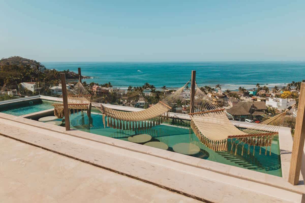 Un espace piscine avec des hamacs et une vue sur l’océan.