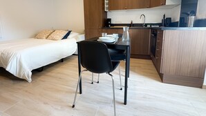 Une pièce de taille modeste comprenant un lit, une table à manger avec des chaises, un coin cuisine et une petite salle de bain.
