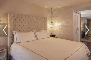 Ein Schlafzimmer mit einer gesteppten Kopfteil, einem Nachttisch und einer hängenden Deckenleuchte.