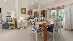 A spacious living room with a dining area, kitchen, and large windows. - Marga-Lisa: Private Pool | Wet Bar | Ensuite Bedrooms (Corolla)