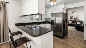 Eine moderne Küche mit weißen Schränken, einem Edelstahlkühlschrank und einer schwarzen Arbeitsplatte.