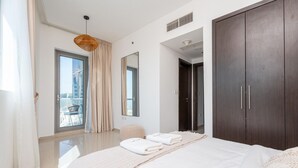 Un dormitorio moderno con una cama grande, un armario oscuro, un espejo y vistas al balcón exterior.