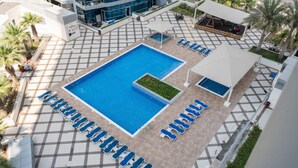 Piscina en la azotea con sillones de descanso y un área de estar techada.