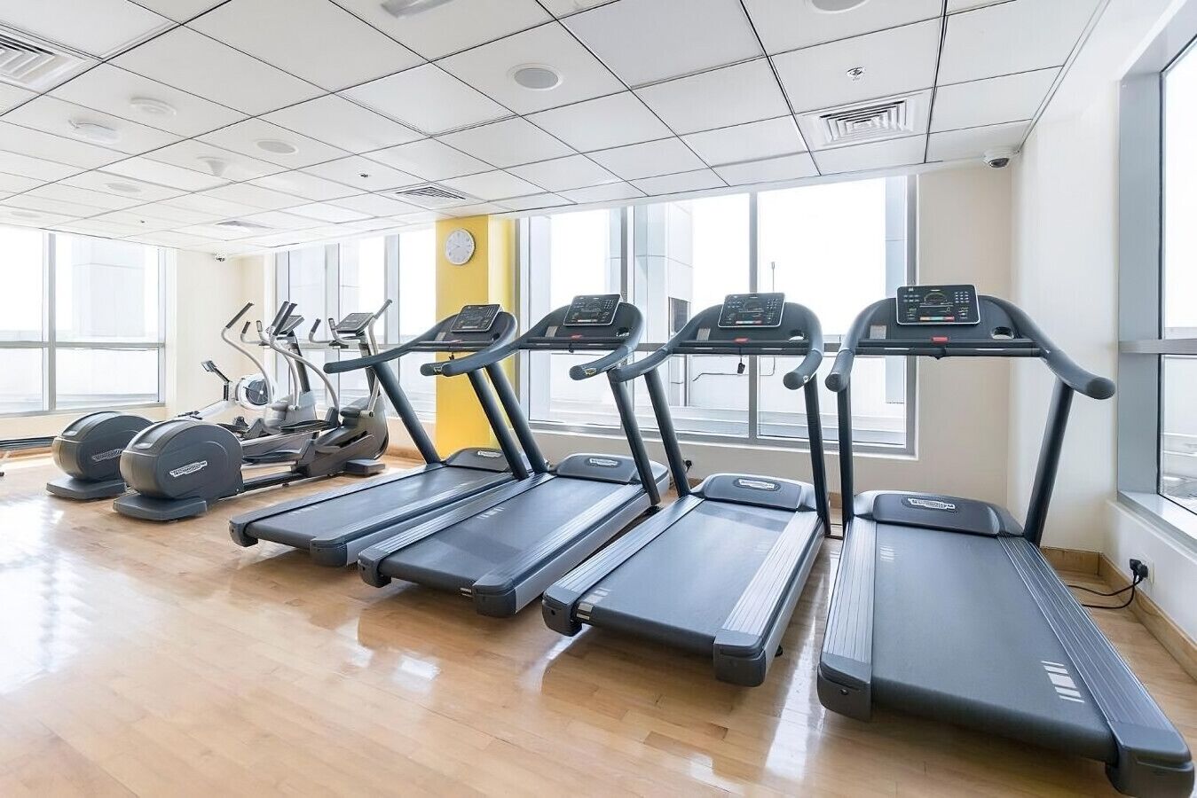 Un gimnasio con cintas de correr, elípticas y una máquina de pesas.