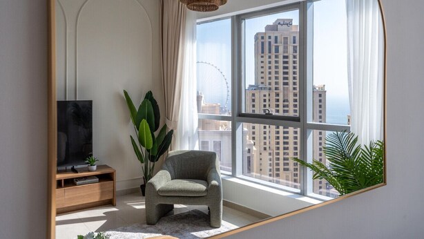 Una sala de estar moderna con un ventanal grande, un televisor, una silla y una planta en maceta.