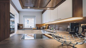 Una cocina moderna con una isla central, electrodomésticos de acero inoxidable y vistas a la ciudad a través de un amplio ventanal.