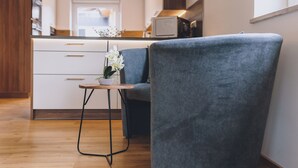Una cocina moderna con armarios blancos, un microondas y una pequeña mesa con una orquídea en maceta.