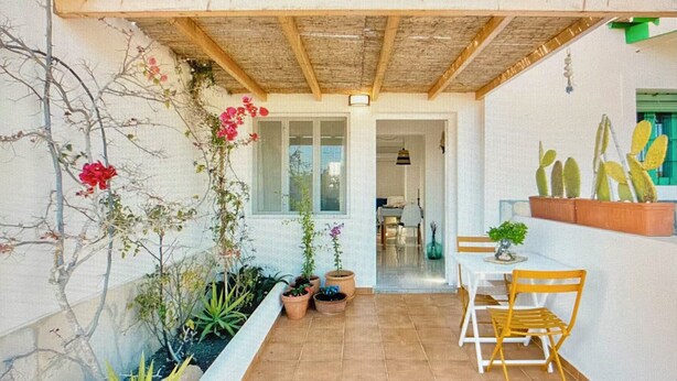 En terrasse med plantekasser, et bord og stole.